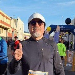 Jaime, corredor, con una sonrisa de satisfacción al cruzar la meta, celebrando su logro tras completar su carrera.